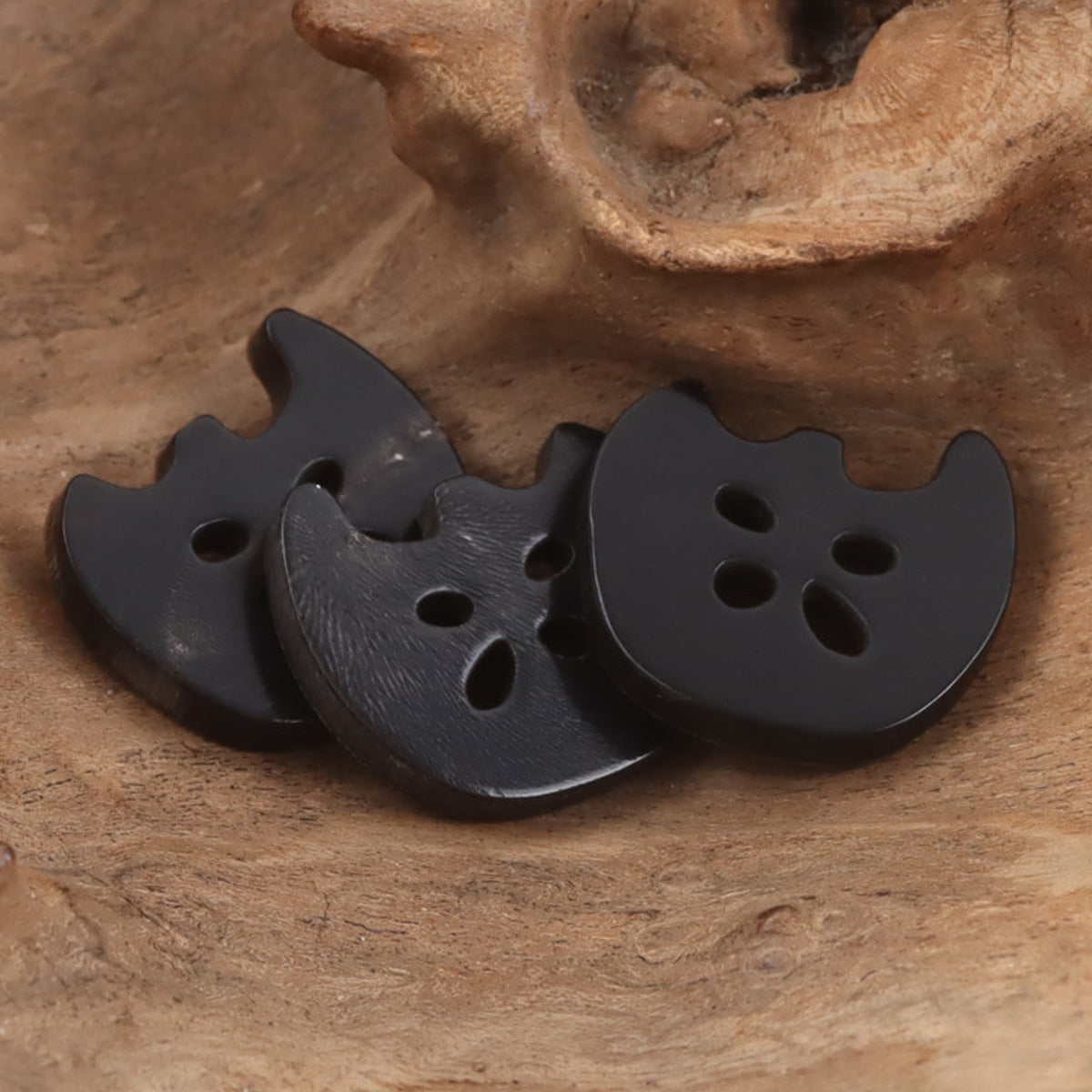 Dark apple-shaped 4-hole cow horn button with rounded scalloped edge
