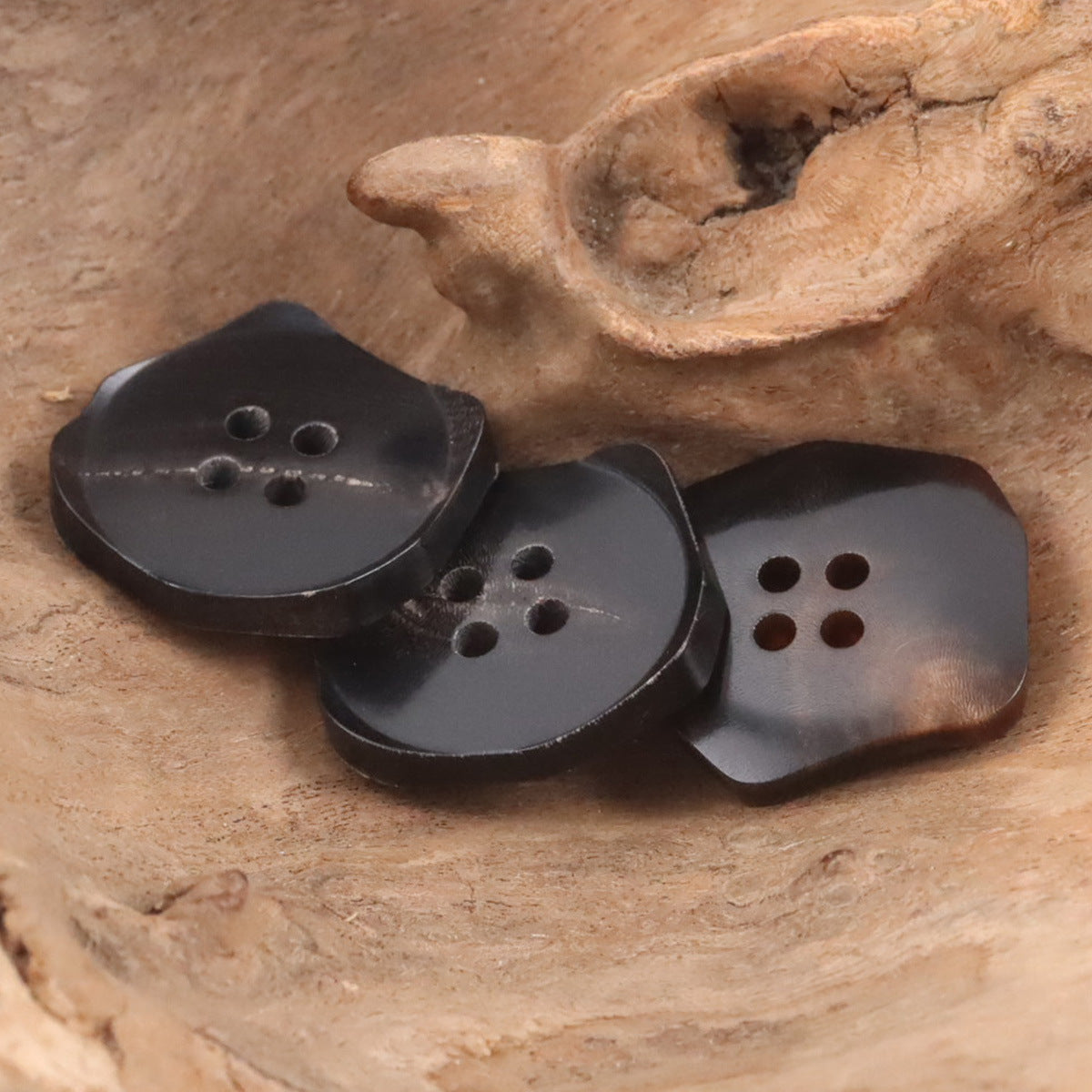 Black exotic-shaped ox horn buttons with four-hole dot patterns