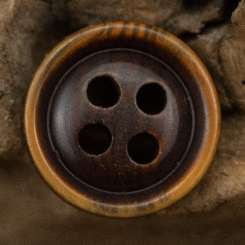 Dark brown resin shirt button with four holes and light rim