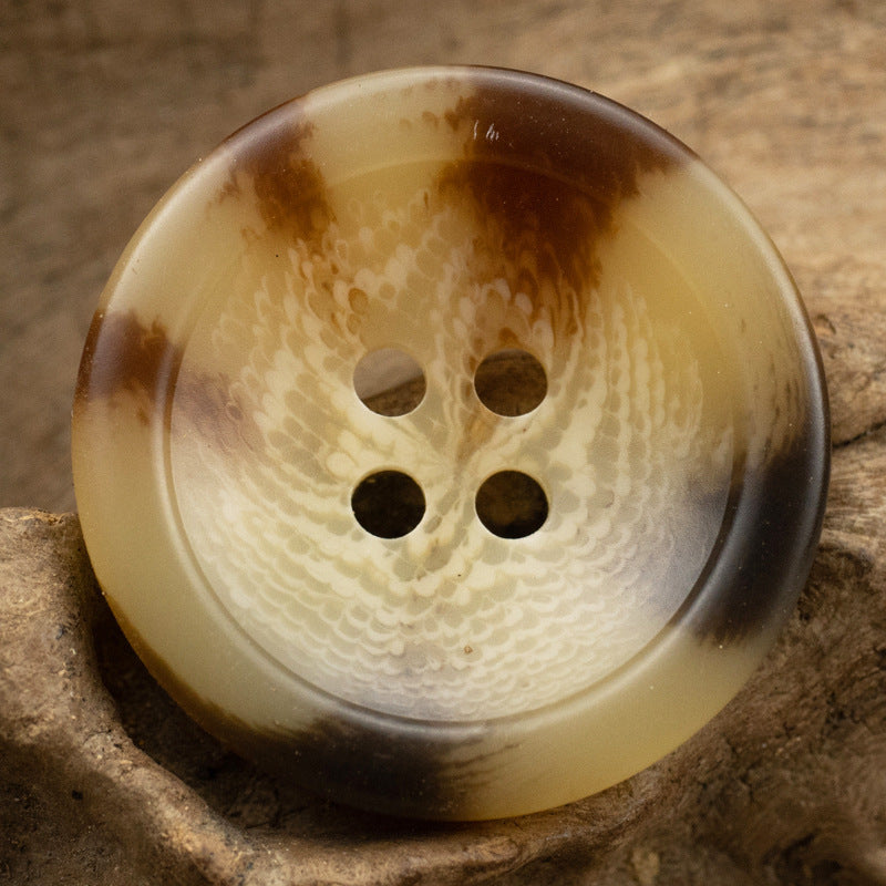Honey-beige resin coat button with four holes and mottled swirl finish