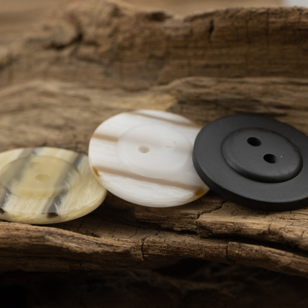 Two-hole resin buttons in off-white and black on wood, close-up