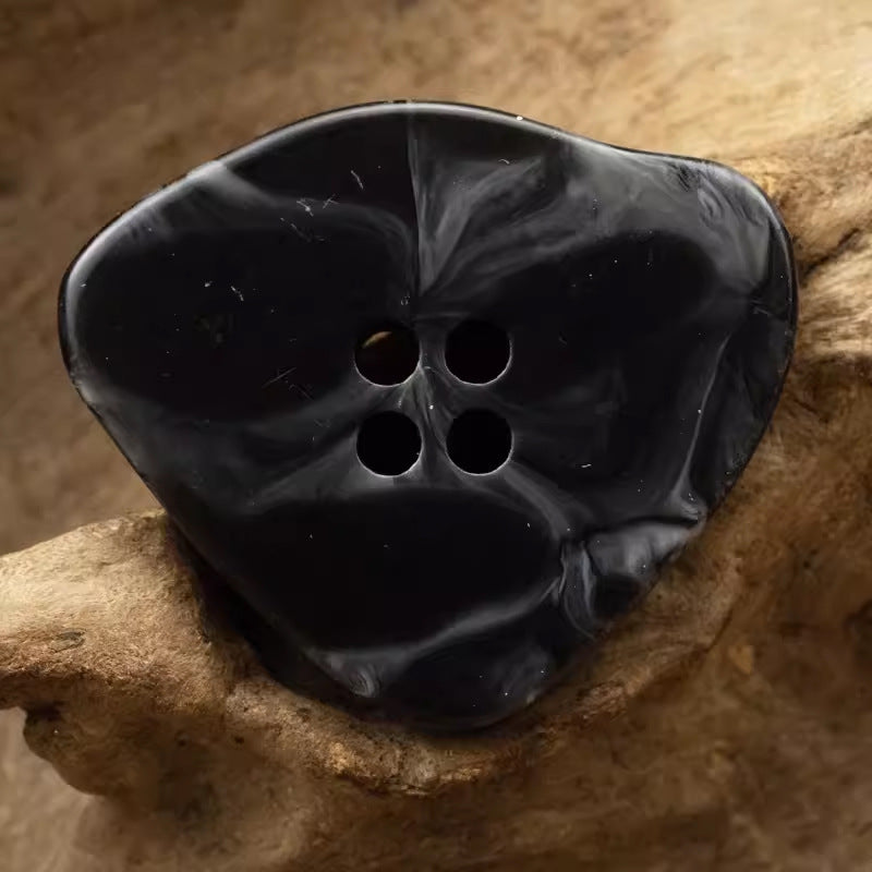 Large irregular resin button, black marble-look with 4 holes.