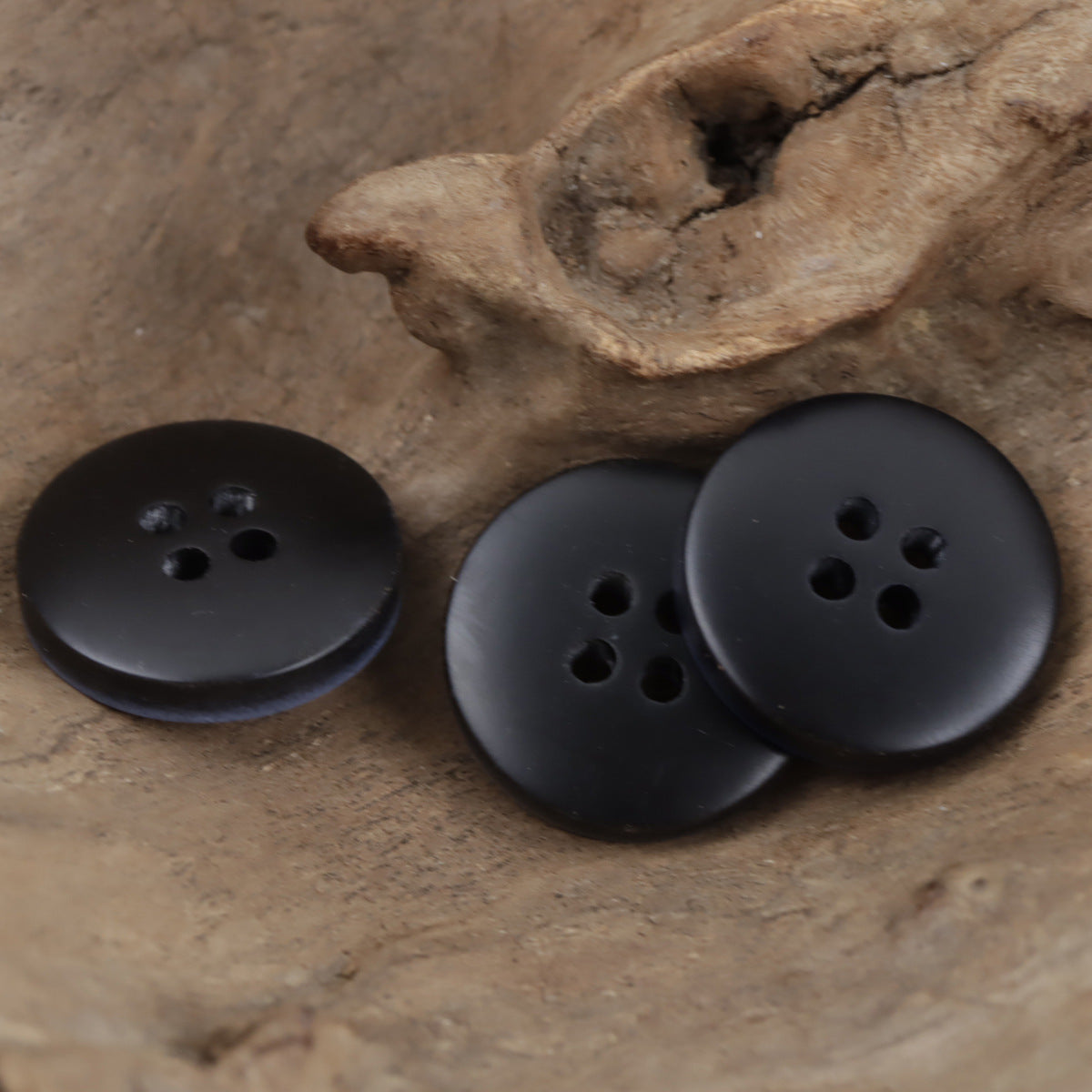 Matte black resin buttons with 4 holes; imitation wood grain finish