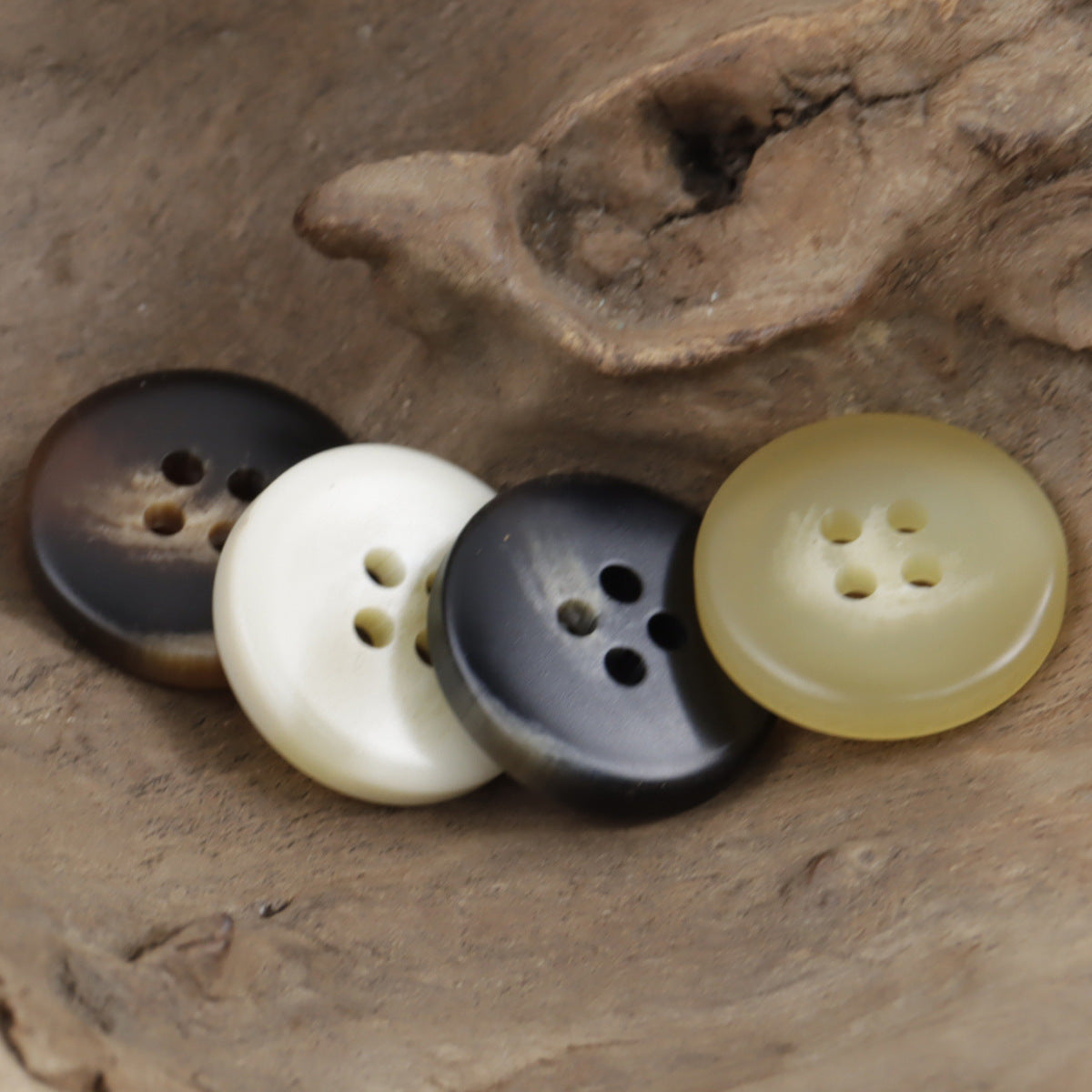 Assorted round 4-hole resin buttons: beige, khaki, dark gray and black on display