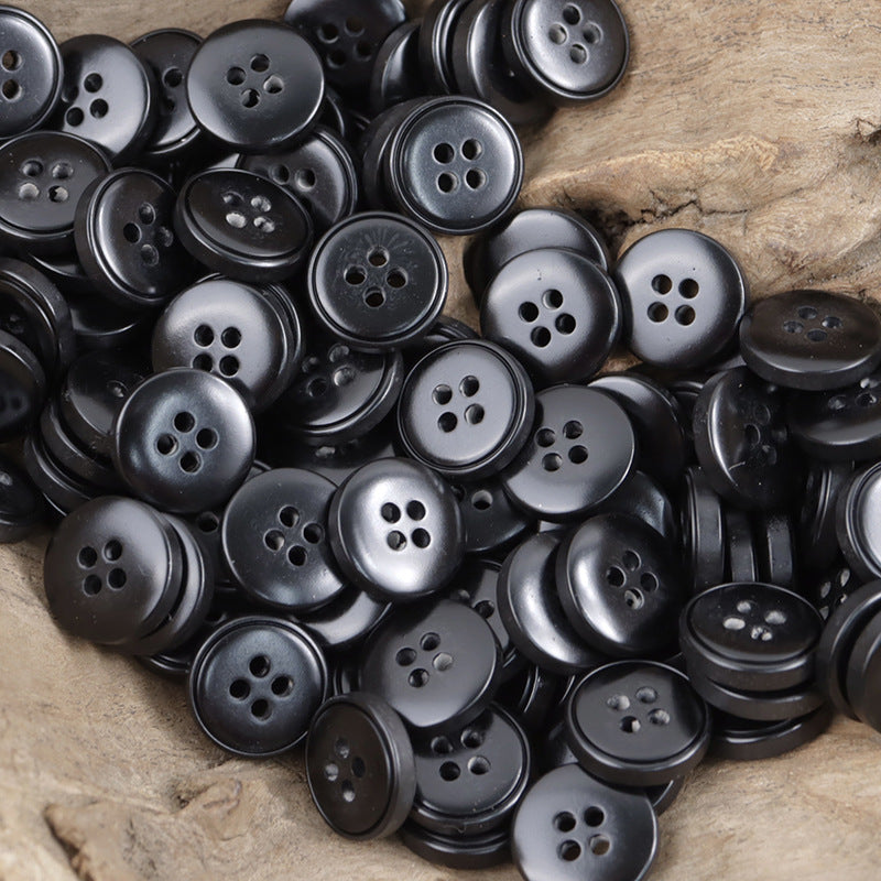 Pile of black round resin buttons with four holes
