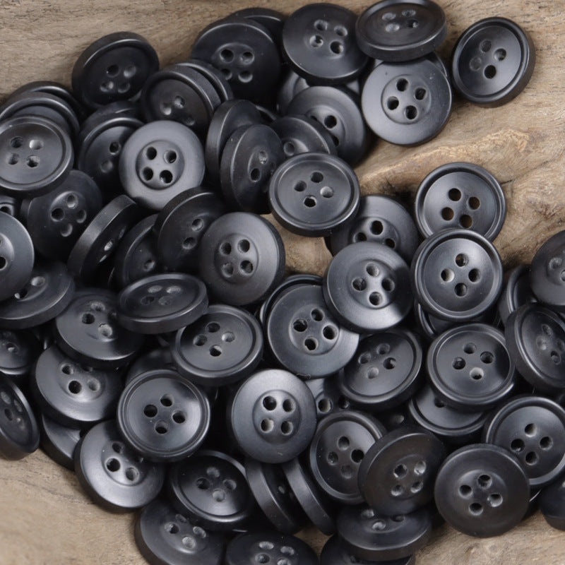 Dark round resin buttons with four holes, scattered pile