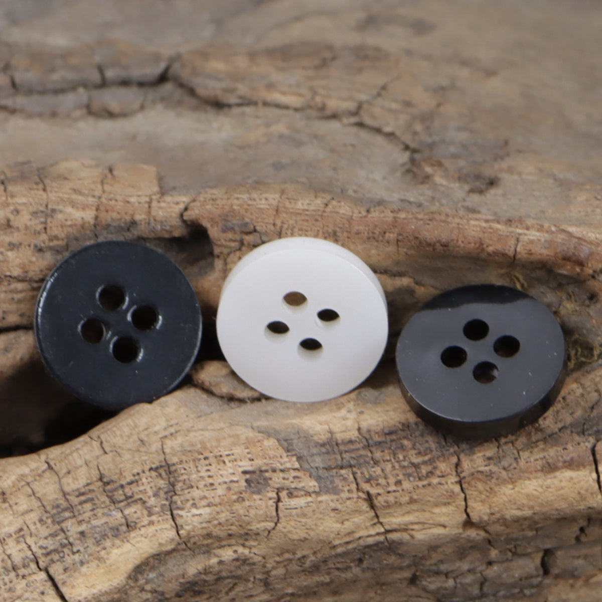 11.5mm round 4-hole resin buttons in white and dark/black, front view