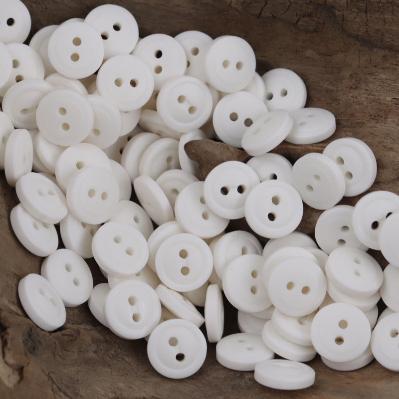 Pile of white resin buttons, round with 4 holes for casual shirts