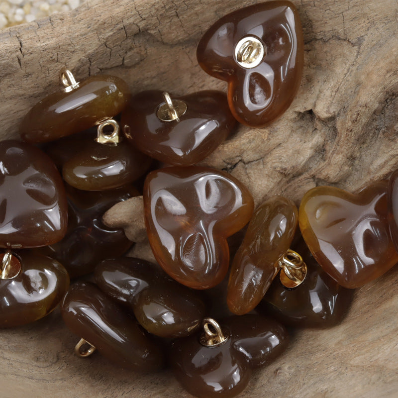 Heart-shaped resin buttons in dark amber/brown with gold-tone metal shanks