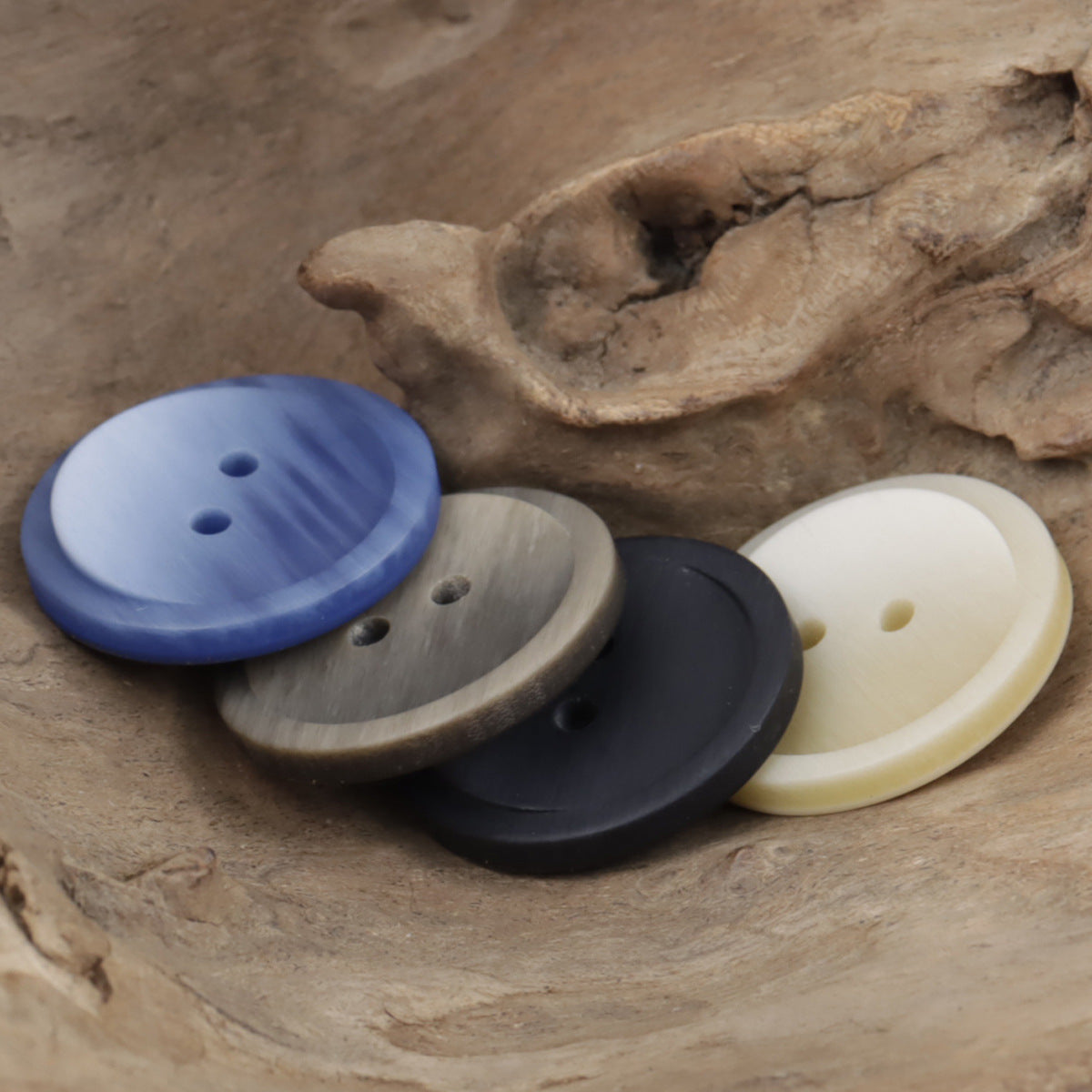 Round two-hole resin buttons in blue, gray, black, and cream gradients