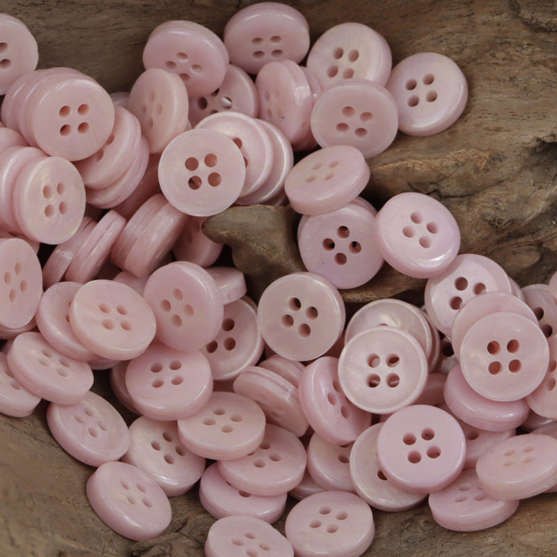 Light pink 4-hole resin buttons pile, round fronts and shank backs (many shown)