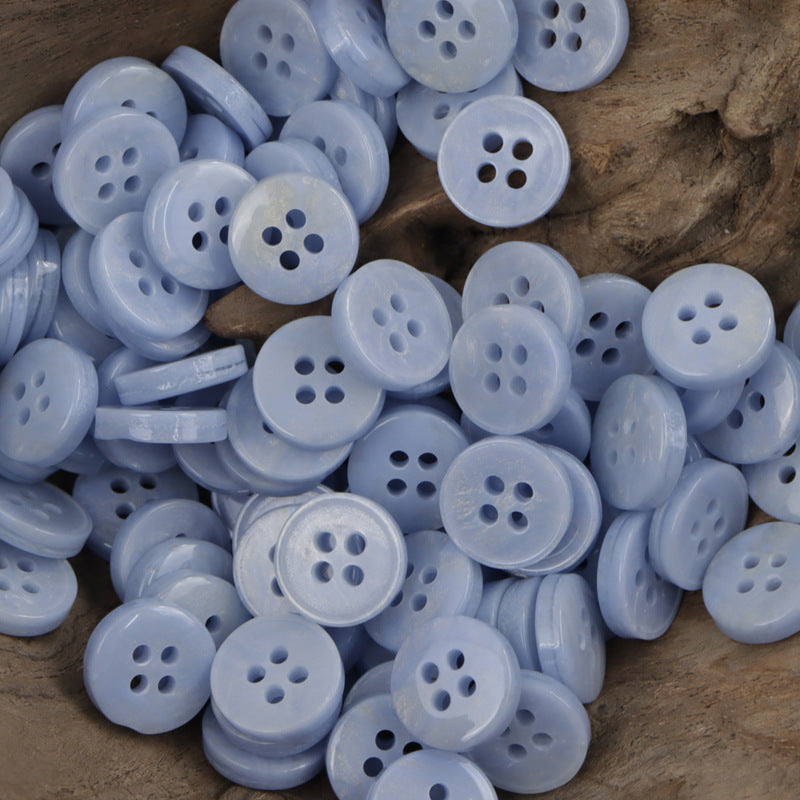 Light blue 4-hole resin buttons pile, round shank-style backs (many shown)