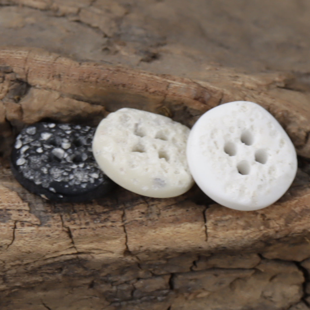 Moon-surface resin buttons in dark and cream, round discs with four holes