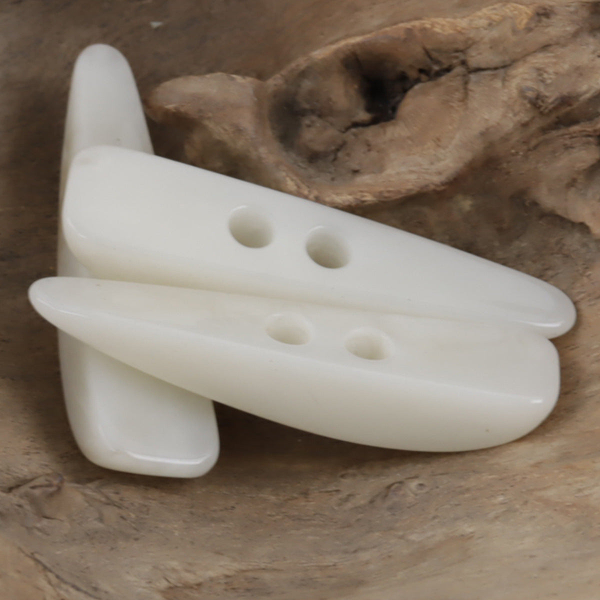 White resin toggle button, long horn-shaped piece with four holes