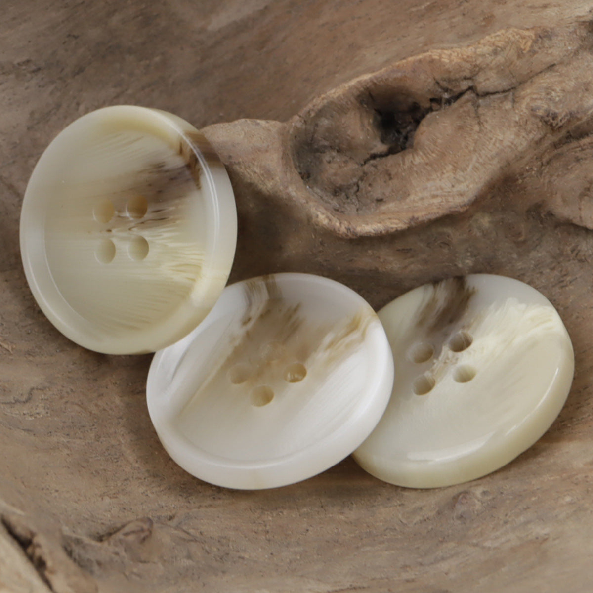 Light khaki resin buttons, round 4-hole design, close-up view of three