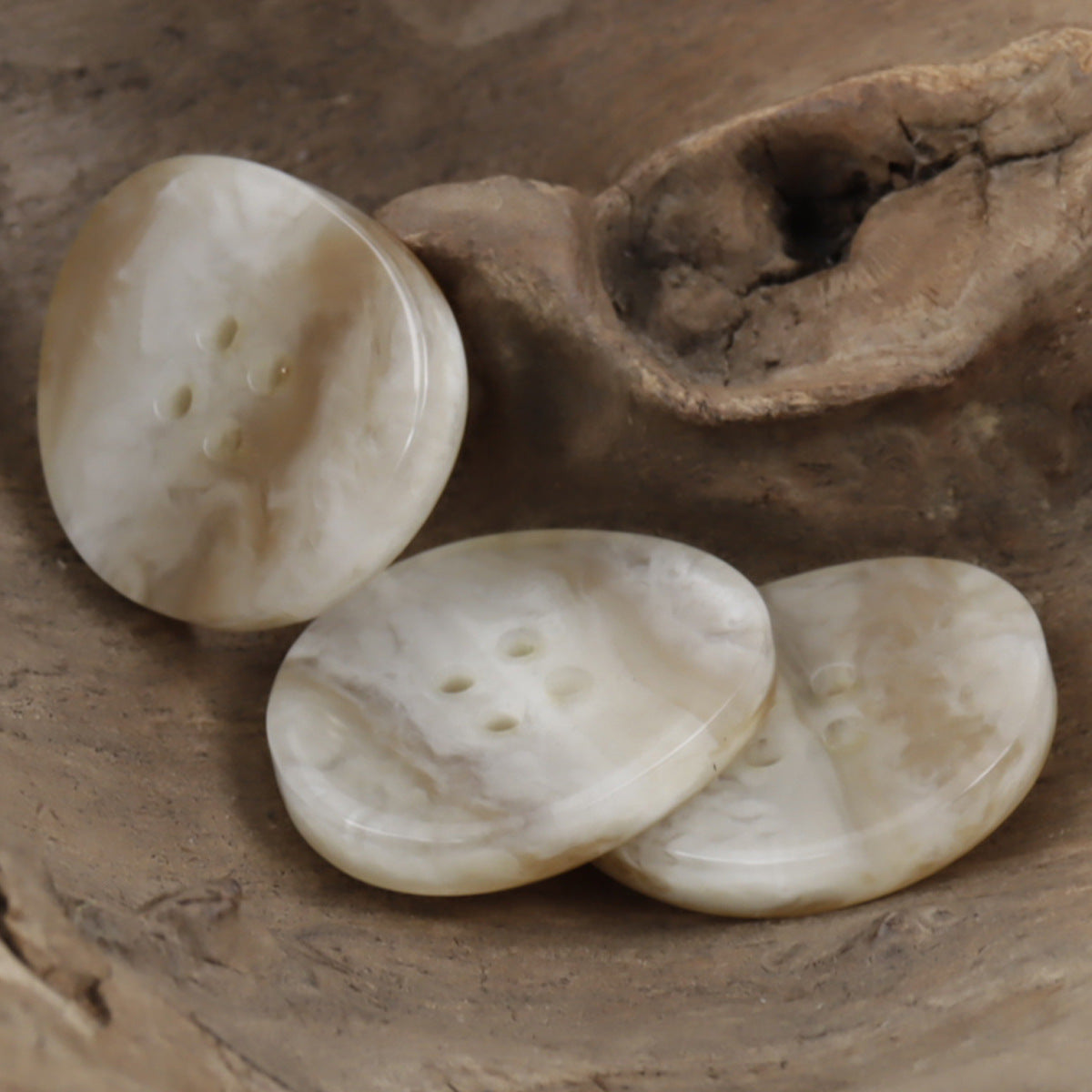 Light khaki resin 4-hole buttons, irregular oval shape, wood-grain veining, group