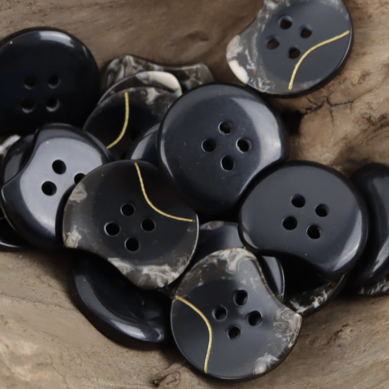 Cardigan resin buttons, dark black with white marbling, four holes, gold curved line
