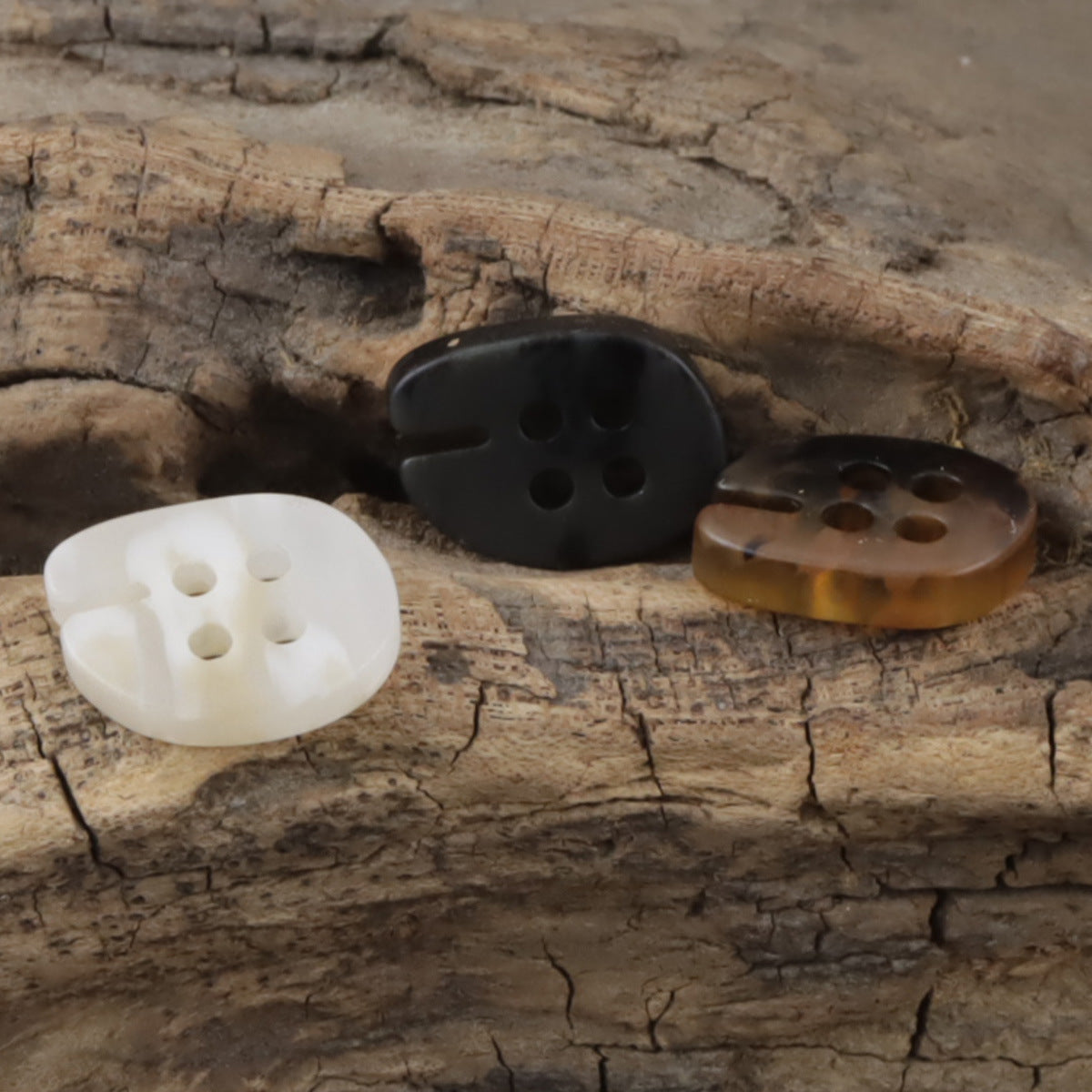 Fish-mouth resin buttons in white, coffee, and black, four-hole front view