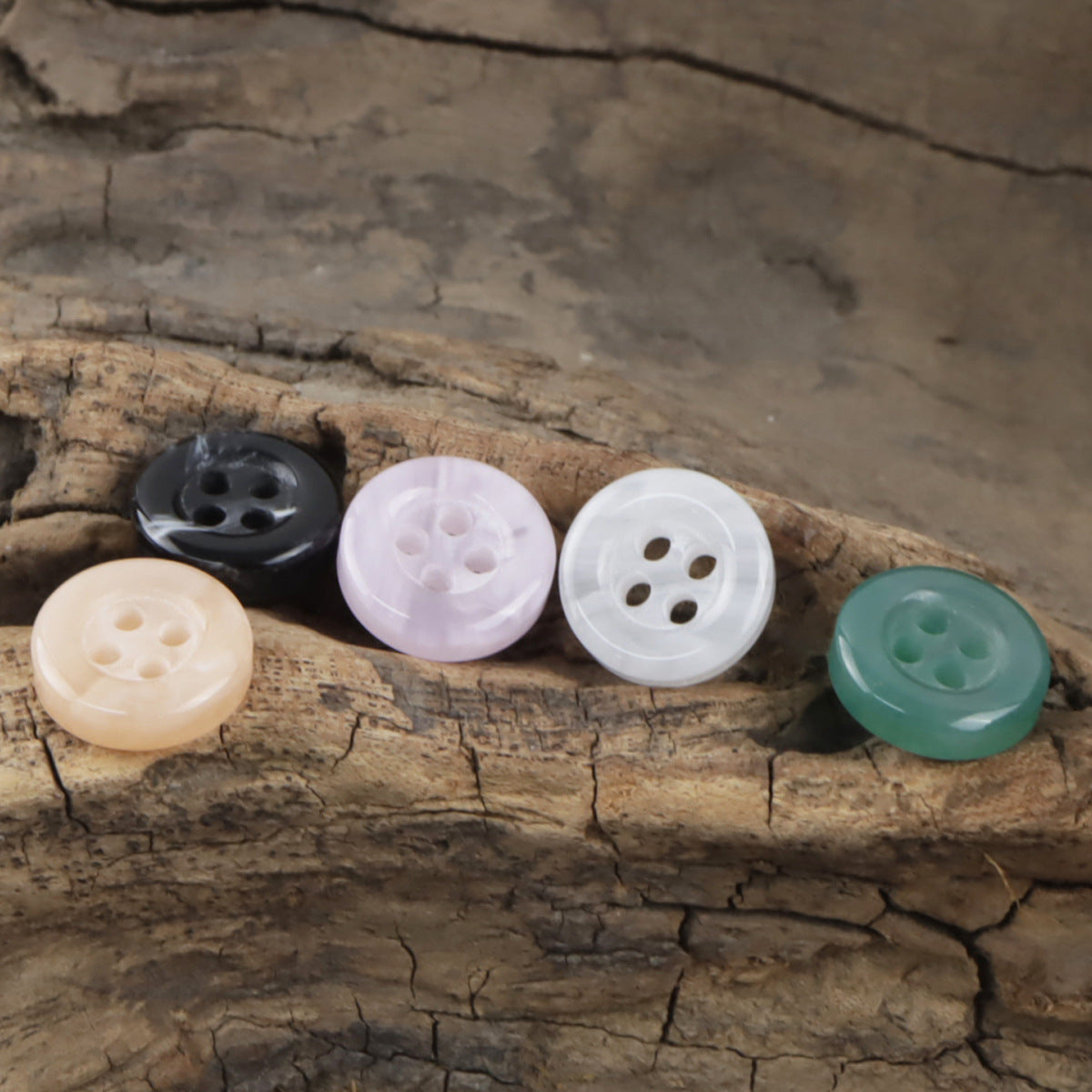 Assorted 11.5mm resin buttons, 4-hole: black, white, cream, teal on wood log