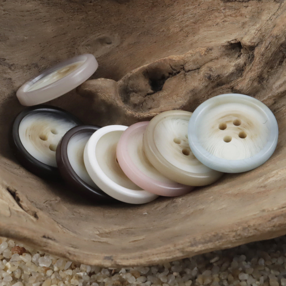 Assorted round resin buttons with 4 holes in white, cream, pink, and black (side angle)