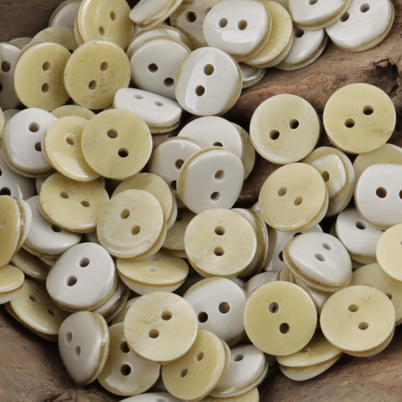 2-hole resin shirt buttons in pale yellow and cream tones, round faces with holes