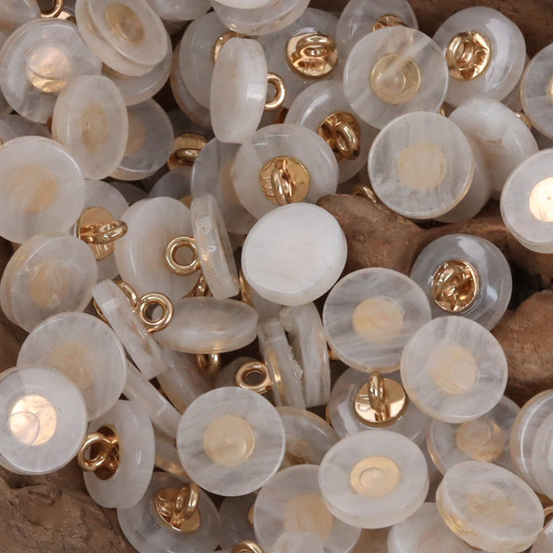 Round resin shank buttons pile in light opal white with gold-tone shanks