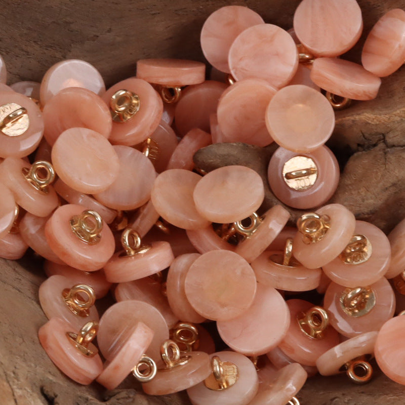 Round resin shank buttons pile in peach/orange with gold-tone shanks