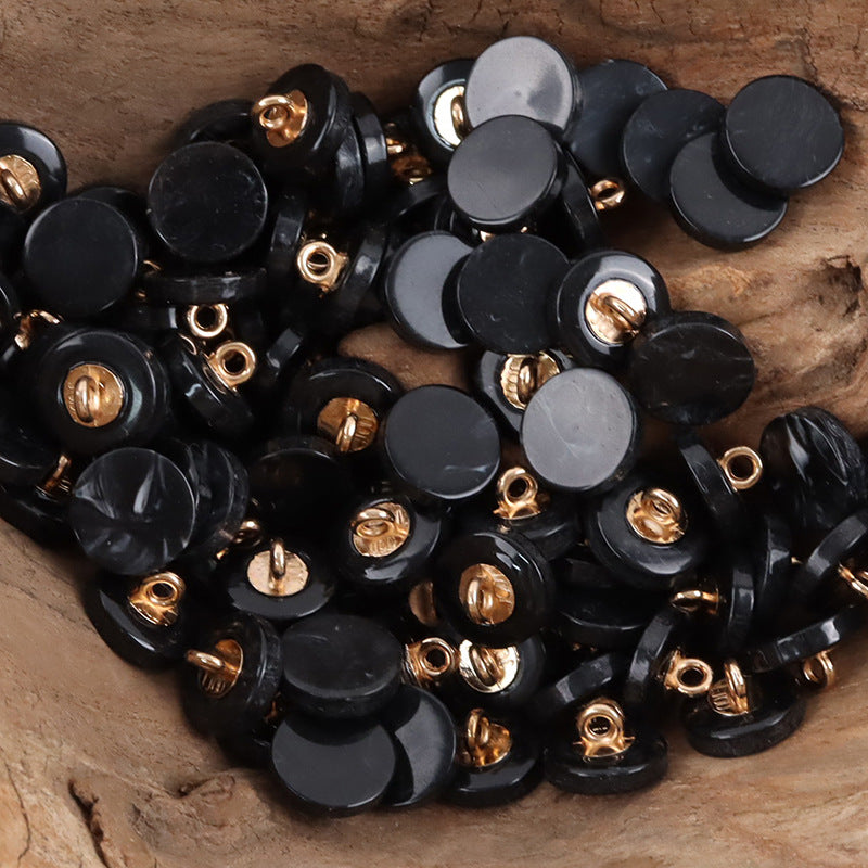 Round resin shank buttons pile in black with gold-tone shanks