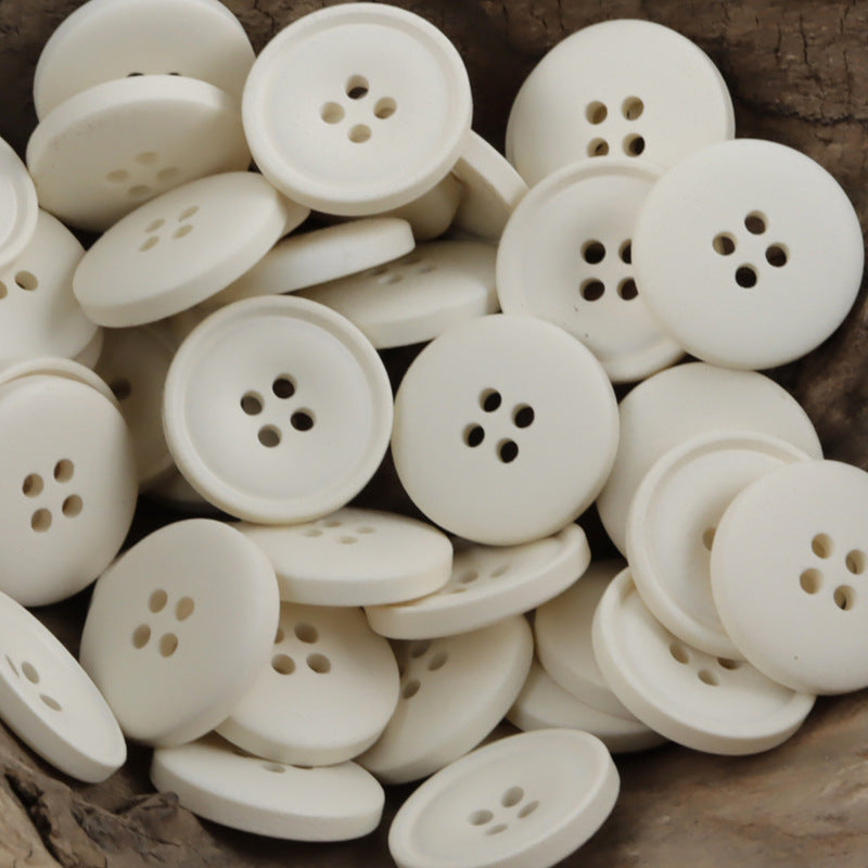 Matte resin coat buttons in off-white/cream with round 4-hole fronts