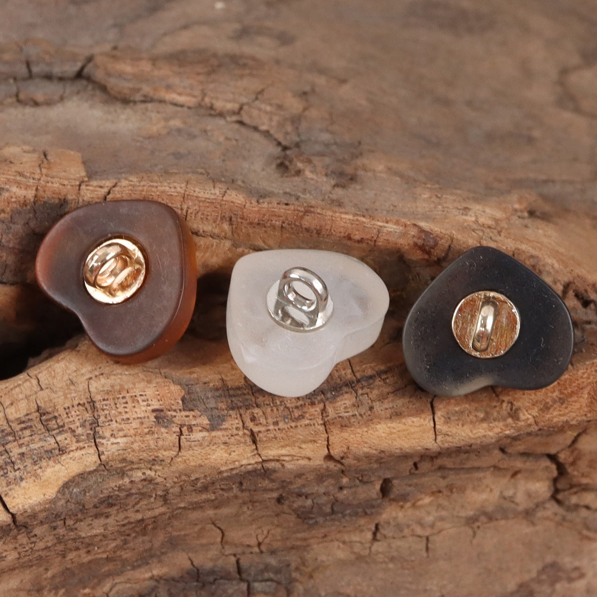Heart-shaped resin buttons with metal shank backs: dark, white, and brown colors.