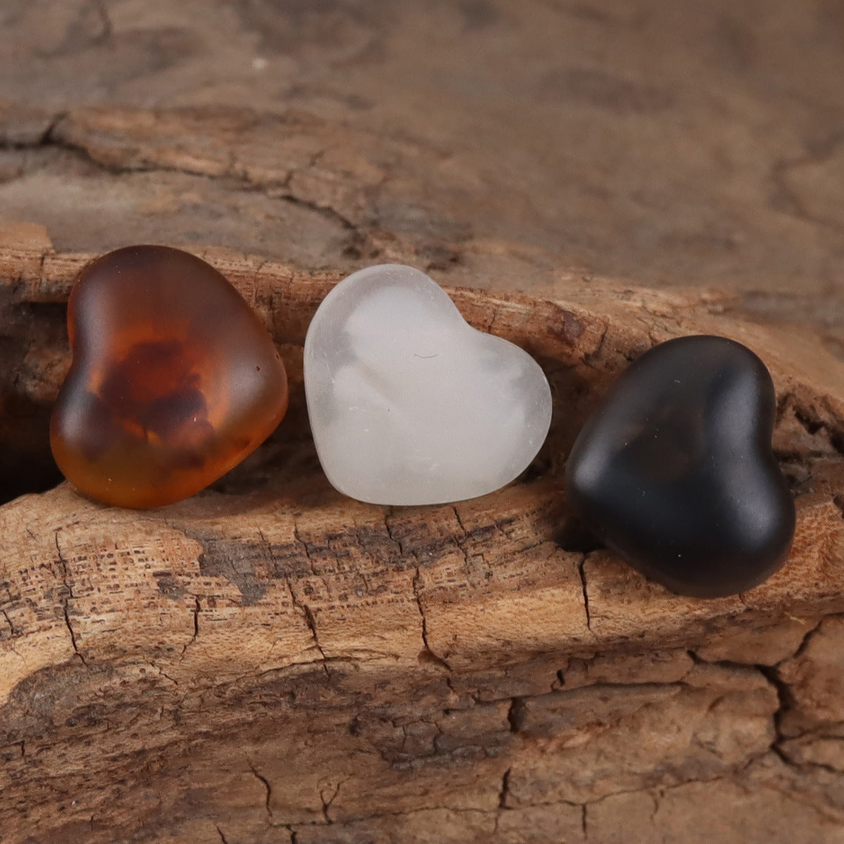 Heart-shaped resin buttons in brown, white, and black on a wooden surface.