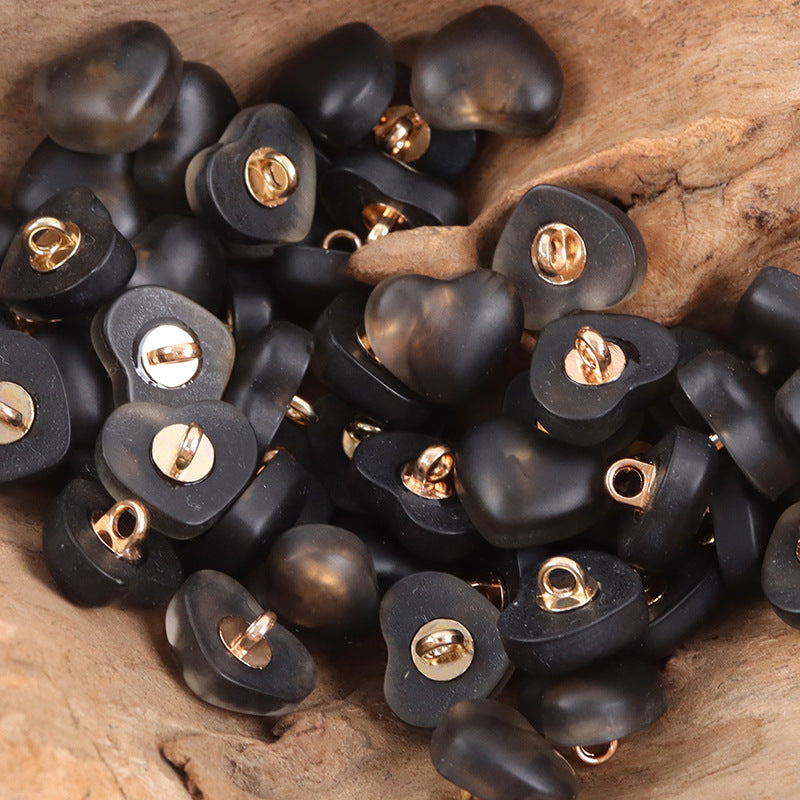 Black heart-shaped resin lingerie buttons, many pieces with gold-toned metal shanks.
