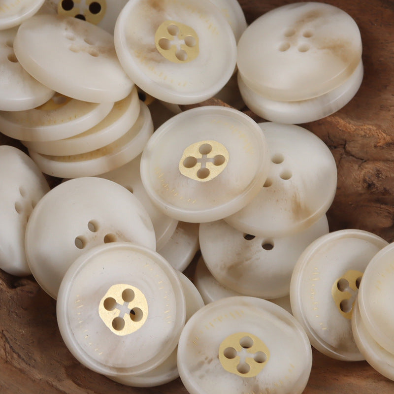 White round resin buttons with four holes and gold-tone shank, close-up