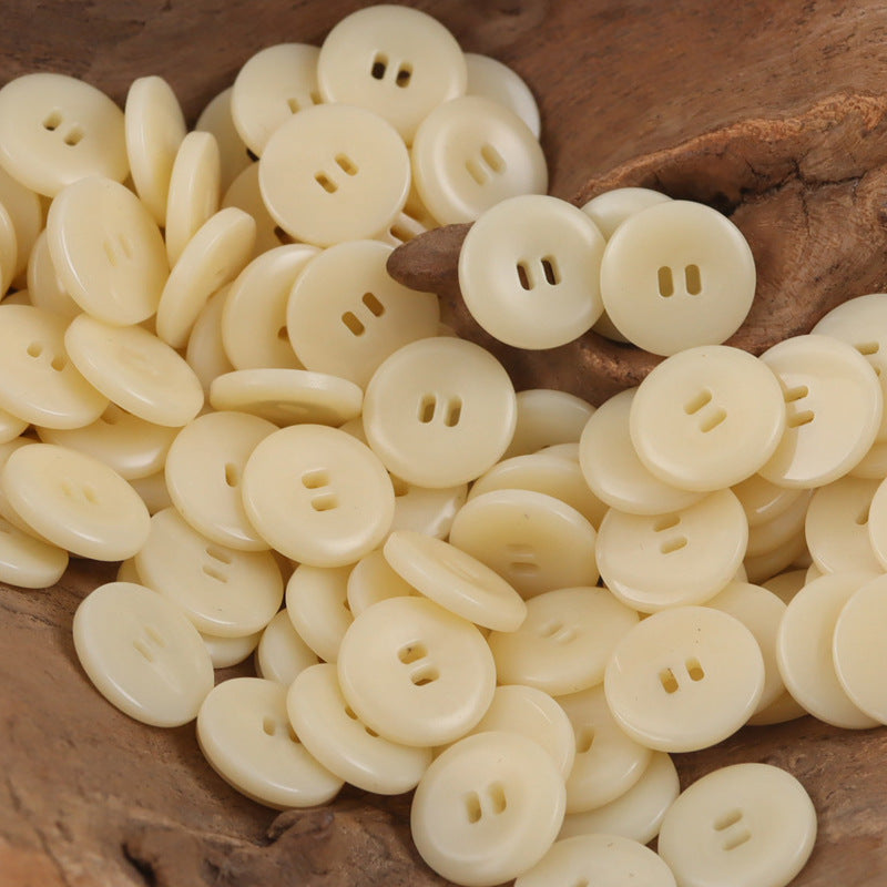 Pile of beige round resin buttons with two-hole and four-hole openings