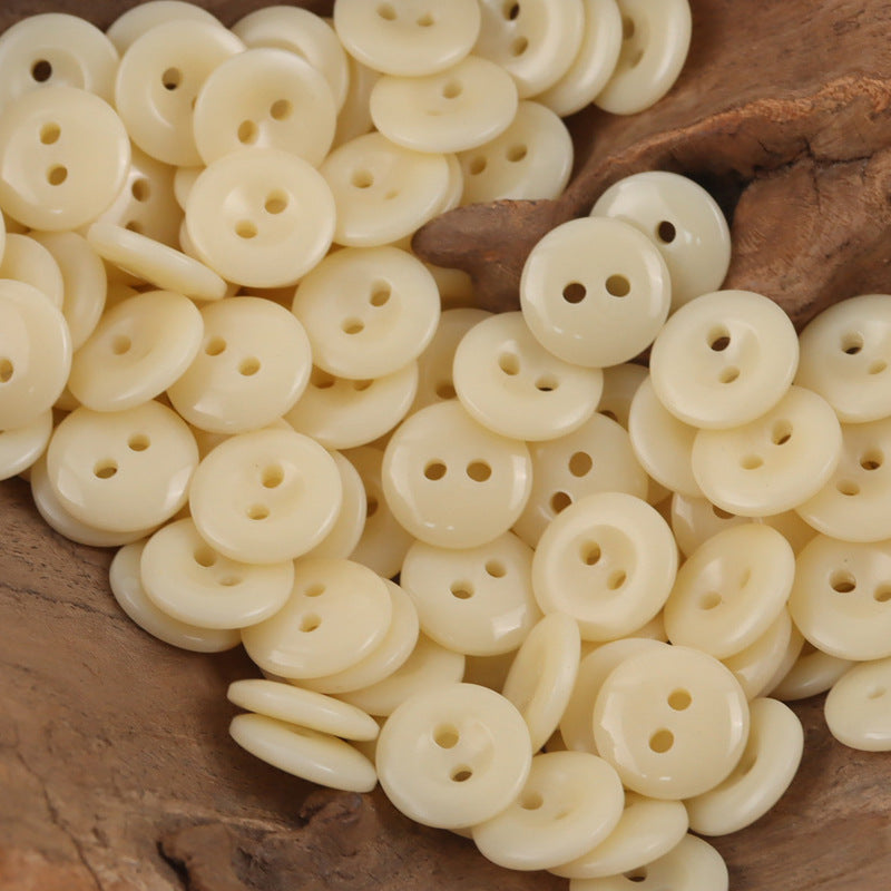 Close-up of beige round resin buttons, showing two-hole and four-hole styles