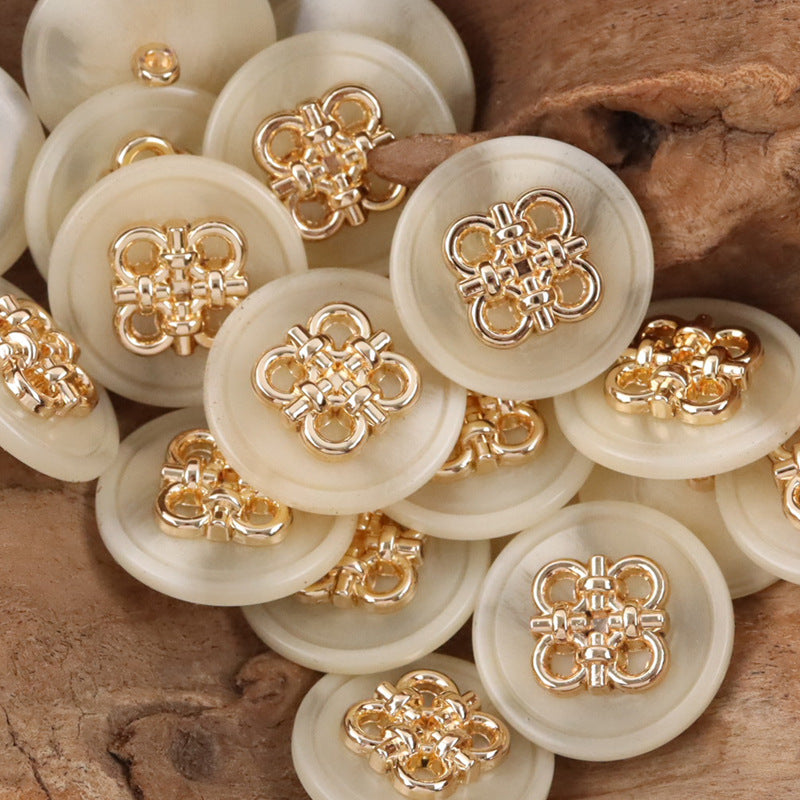 Ivory resin coat buttons with Chinese knot style metal fronts and metal shanks, close view