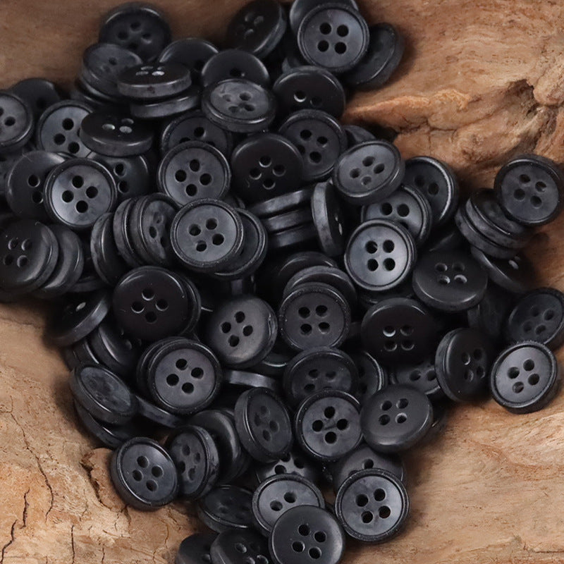 11.5mm black resin buttons, round four-hole style, bulk pack on wood