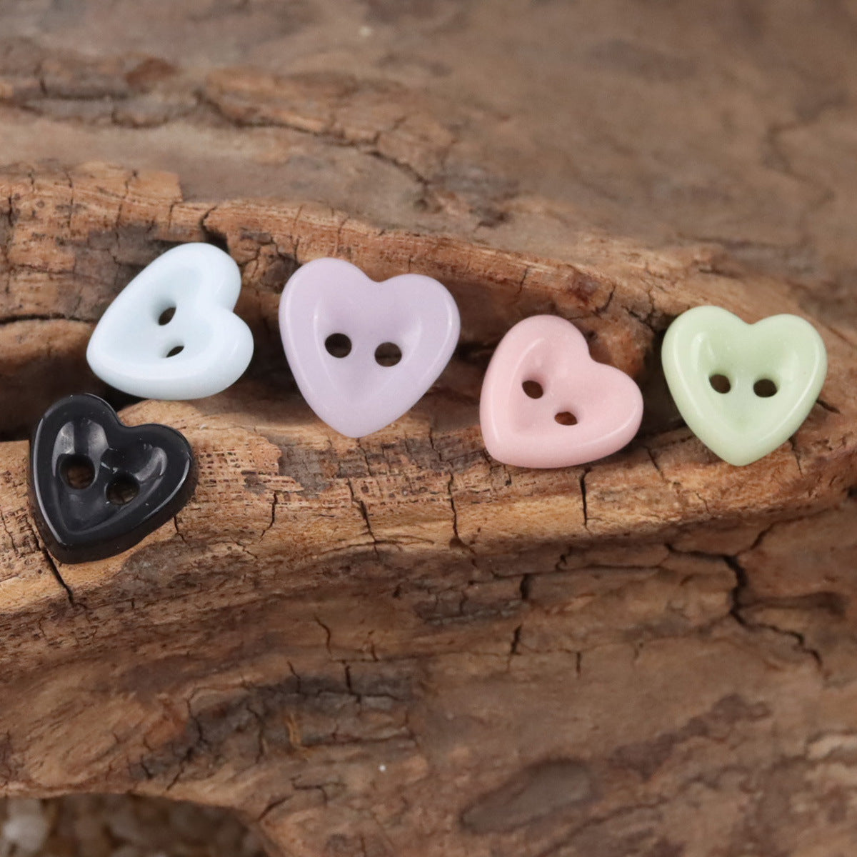 Ceramic heart buttons in white, lavender, pale pink, mint green, and black with two holes.