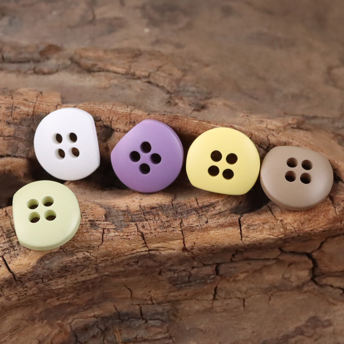 Mixed pastel semi-circular resin buttons with four holes on wood surface