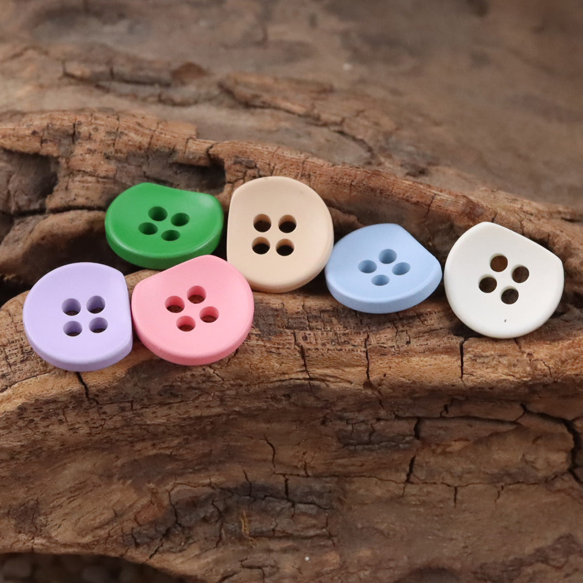 Assorted semi-circular resin buttons with four holes: green, pink, blue, white, purple