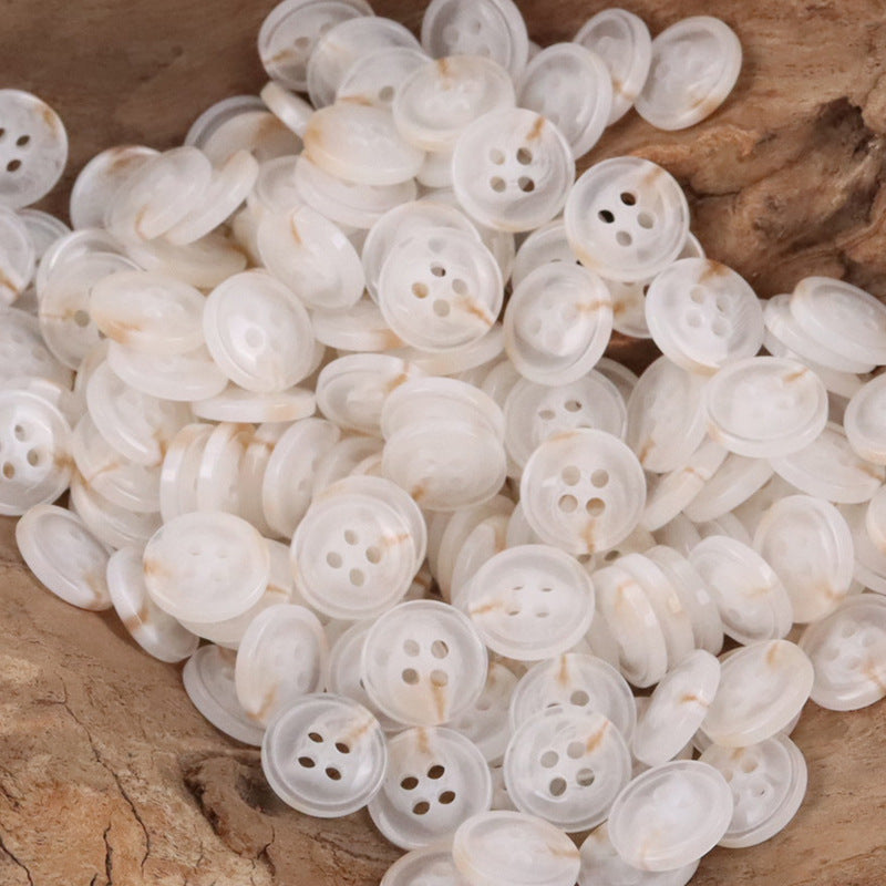Pile of semi-transparent resin shirt buttons, off-white/cream, four-hole