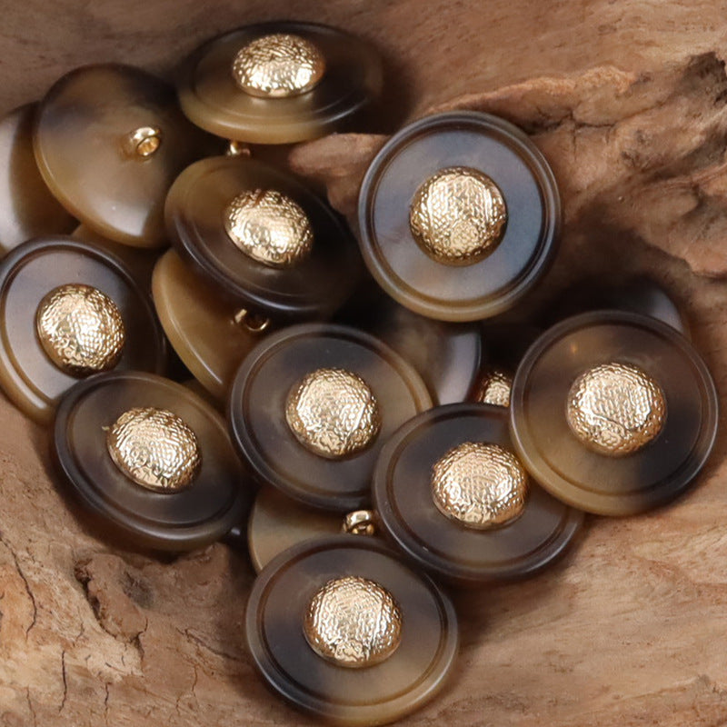 Mixed resin buttons with gold-tone caps and metal shanks on dark gray and tan bases