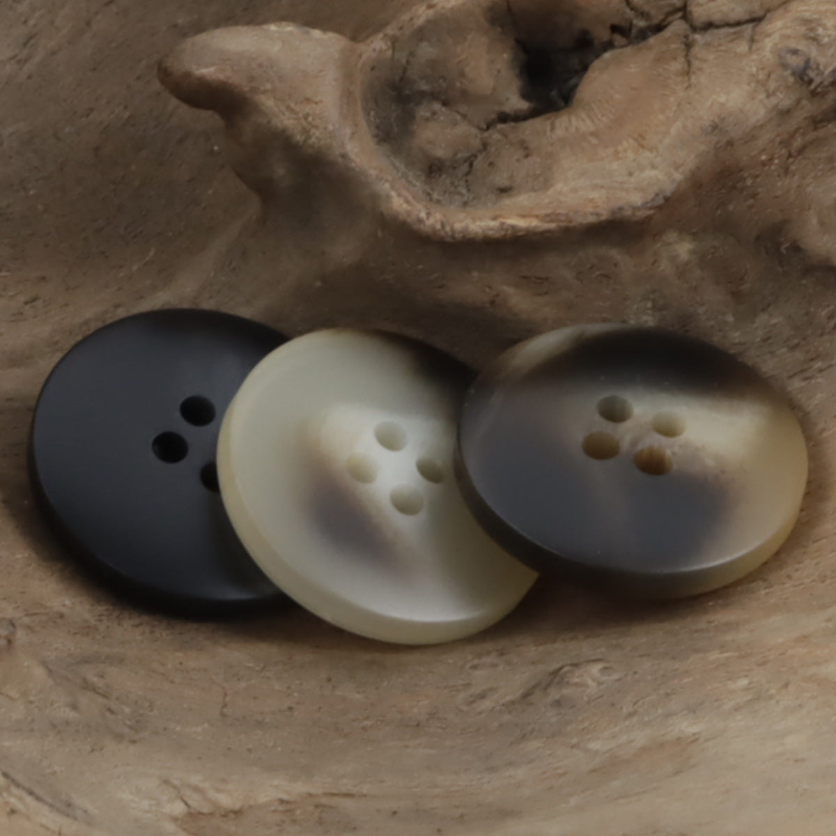Three round resin buttons: dark, cream, and beige, each with 4 holes