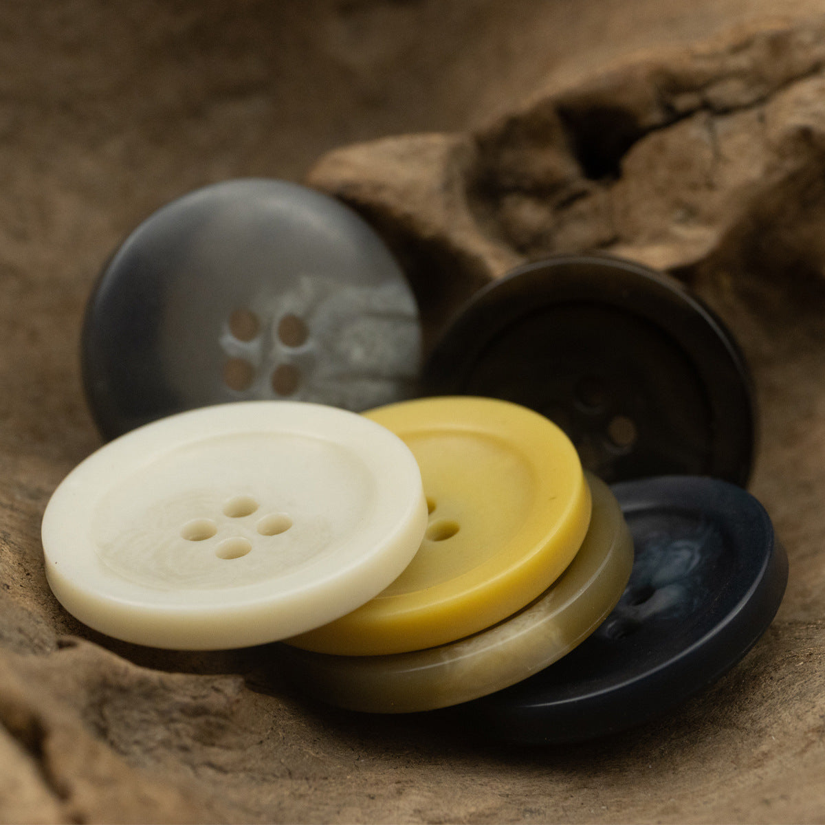 4-hole coat buttons in cream, yellow, dark gray and black tones, stacked