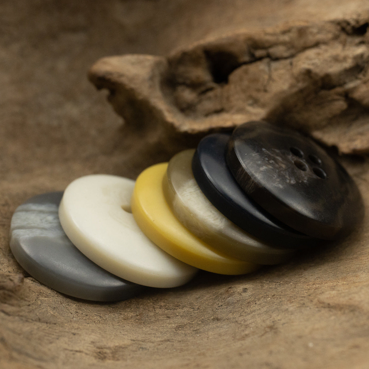 Stack of 4-hole coat buttons: cream, yellow, light gray, dark gray and black