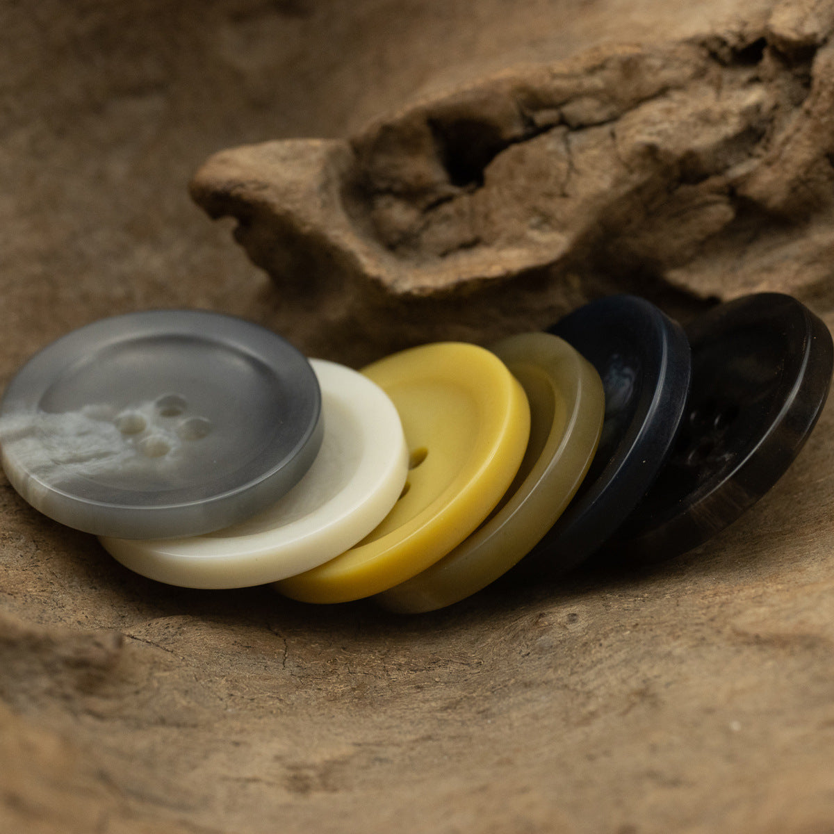 Stacked 4-hole coat buttons: light gray, cream, yellow, dark gray and black