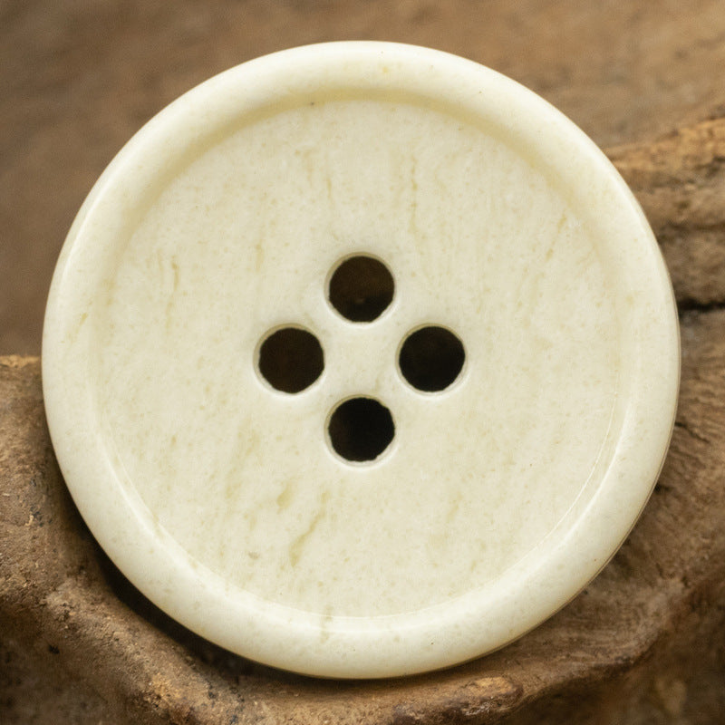 White round 4-hole urea-look button with slim edge and fruit-texture pattern