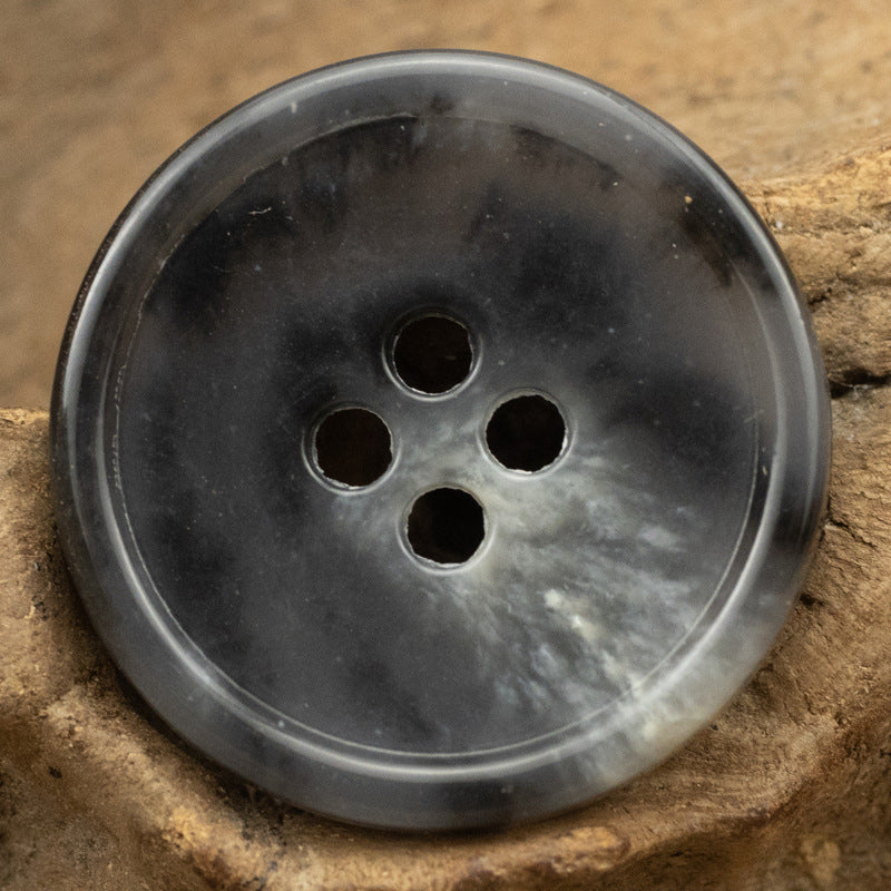 Dark gray round 4-hole urea-look button with slim edge and imitation fruit texture
