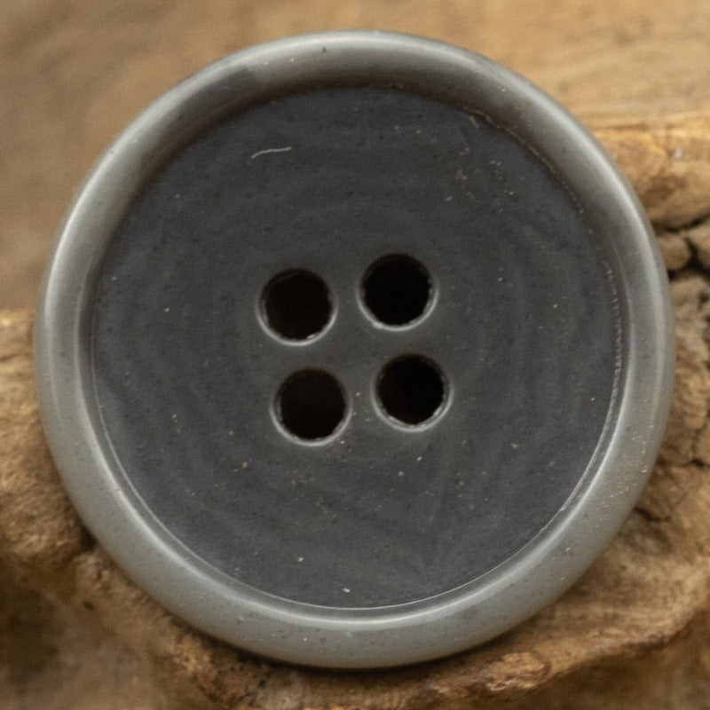 Dark gray round 4-hole button with slim edge, urea-look finish, fruit texture