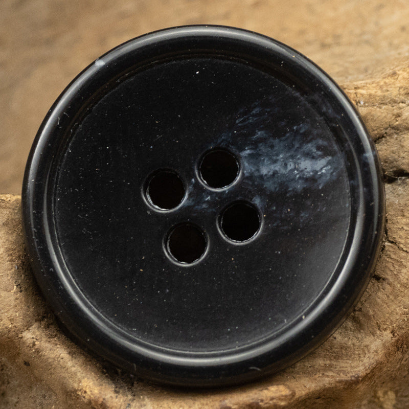 Black round 4-hole urea-look button with slim edge and fruit-texture finish